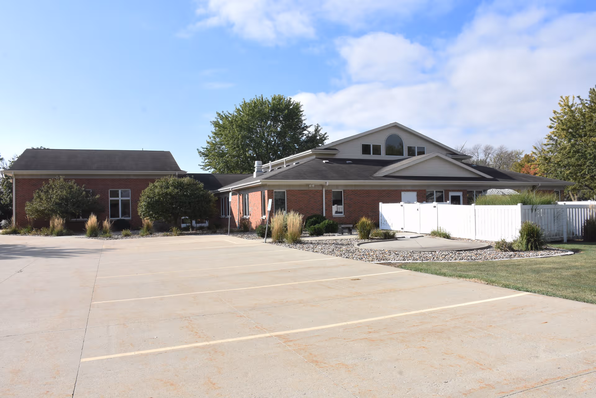 Brick exterior of a senior living facility with a parking lot and landscaped entry.