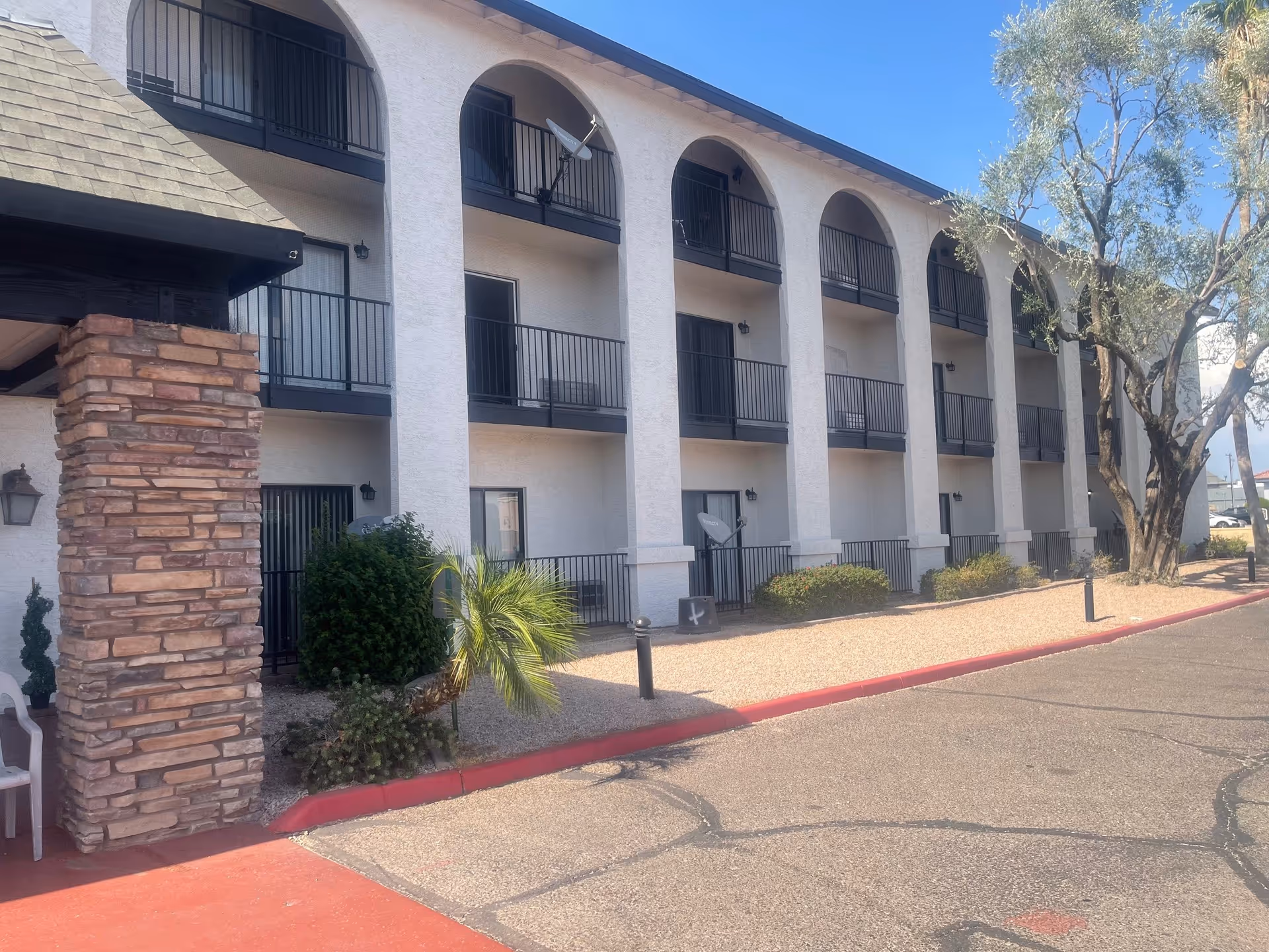 Two-story senior living building with arched balconies and desert landscaping along the front.