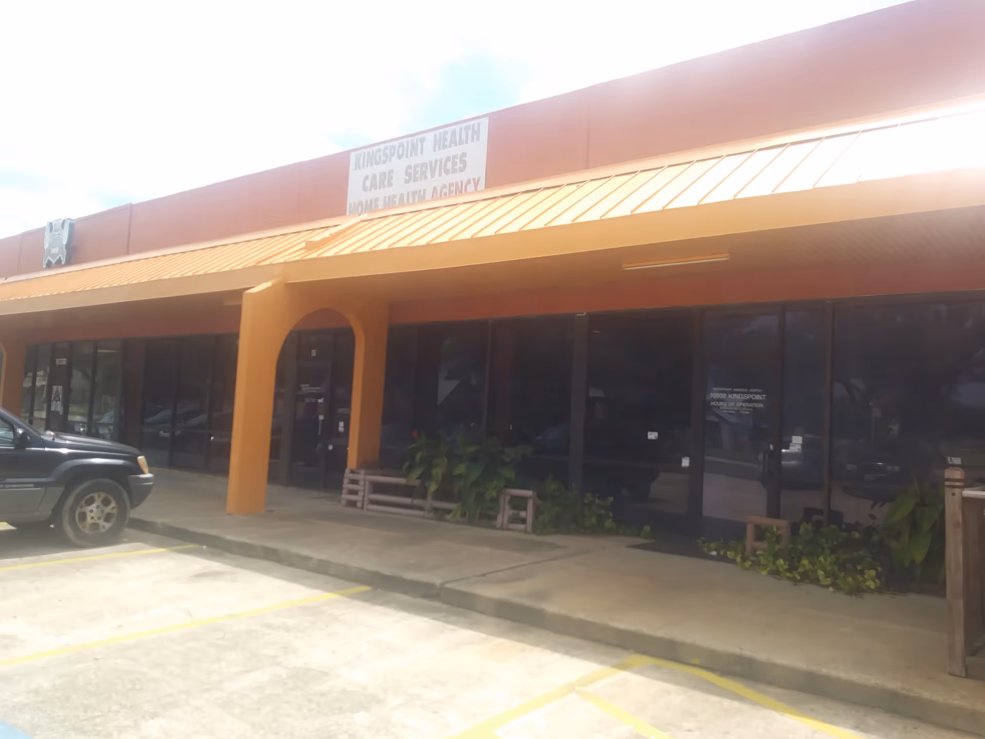 Exterior view of Kingspoint Healthcare Services storefront with glass doors and parked car.