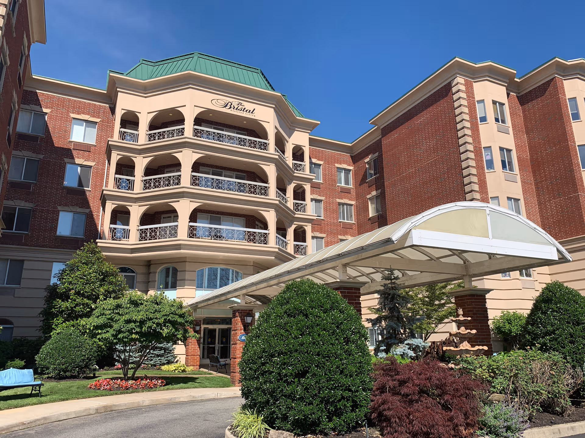 Exterior view of The Bristal Assisted Living at East Meadow with a curved entrance canopy.