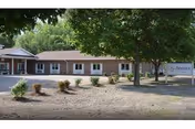 Single-story brick building with multiple windows, trees, and a sign reading Accura HealthCare of Ames.