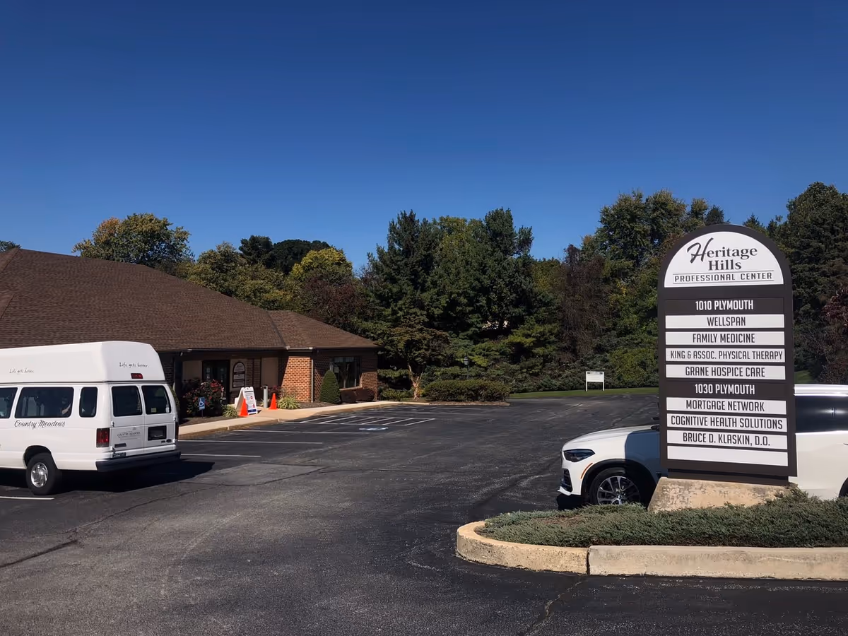 Exterior view of Heritage Hills Professional Center with a tall sign and a white van.