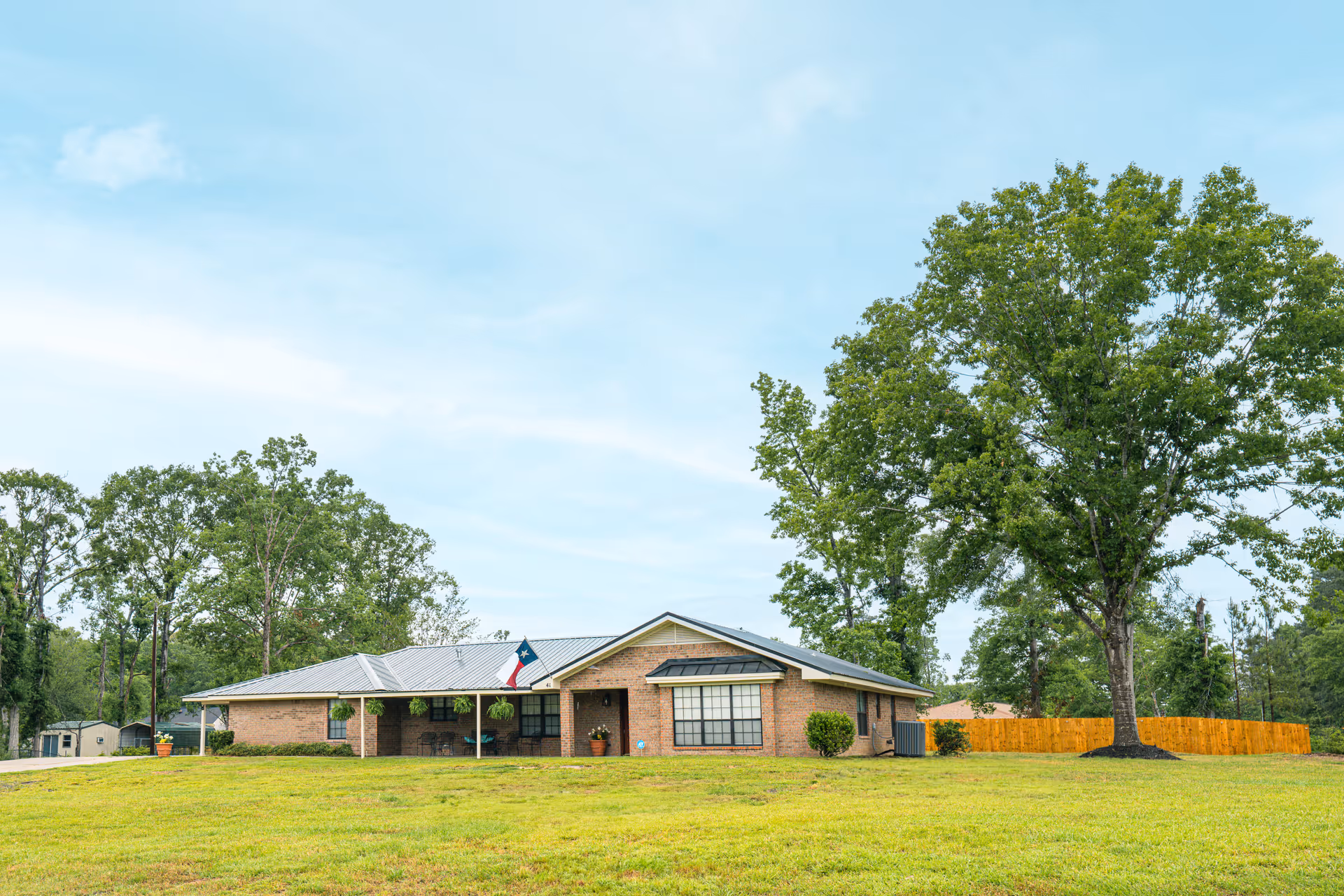 Single-story brick senior living facility with a manicured lawn and large trees