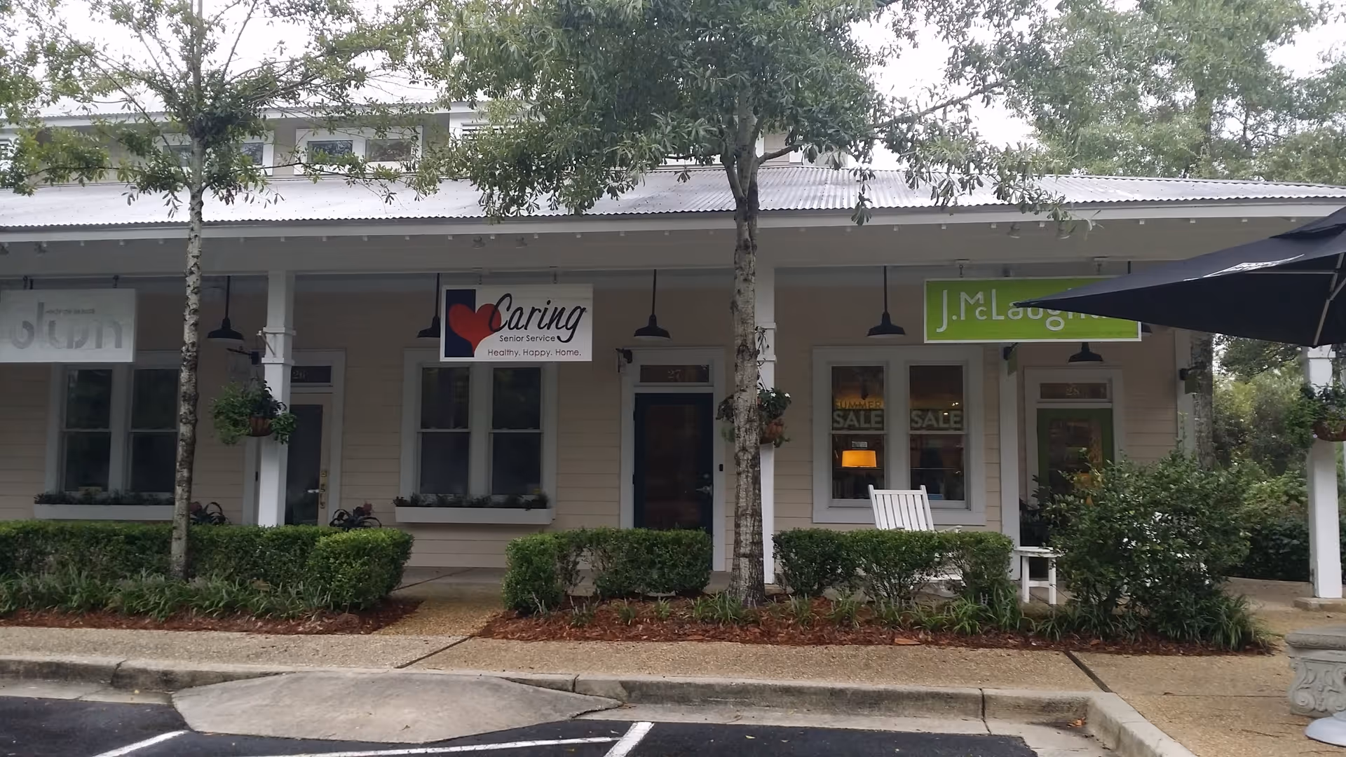 One-story storefront for Caring Senior Service with signage and greenery in front.