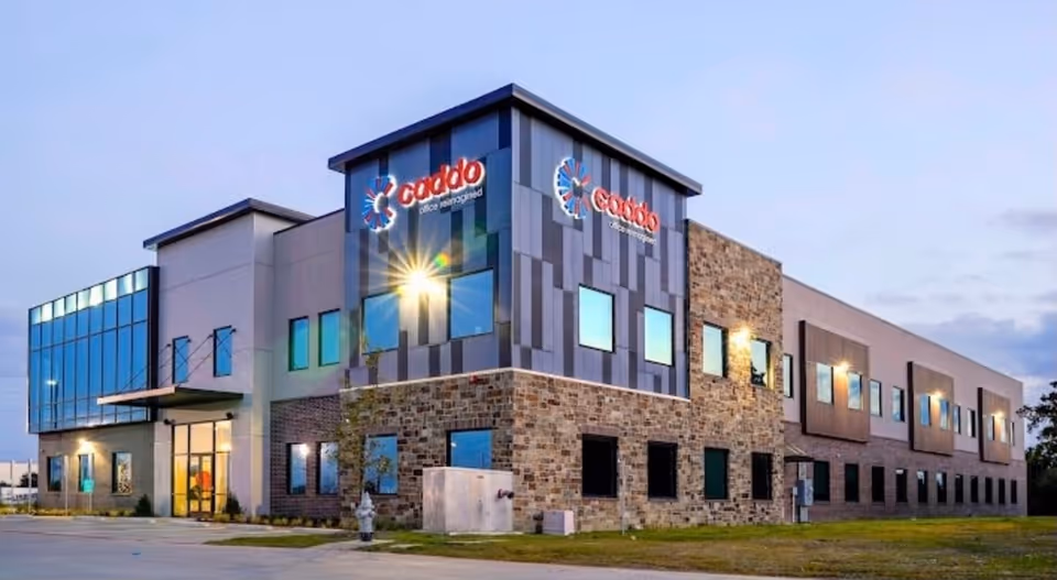 Modern two-story facility exterior with stone and metal panels, large windows, and a prominent entrance.