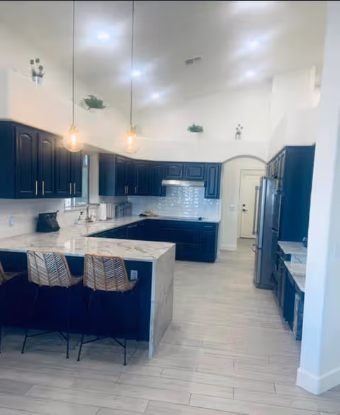 Modern kitchen with dark blue cabinets, white countertops, and a central island.