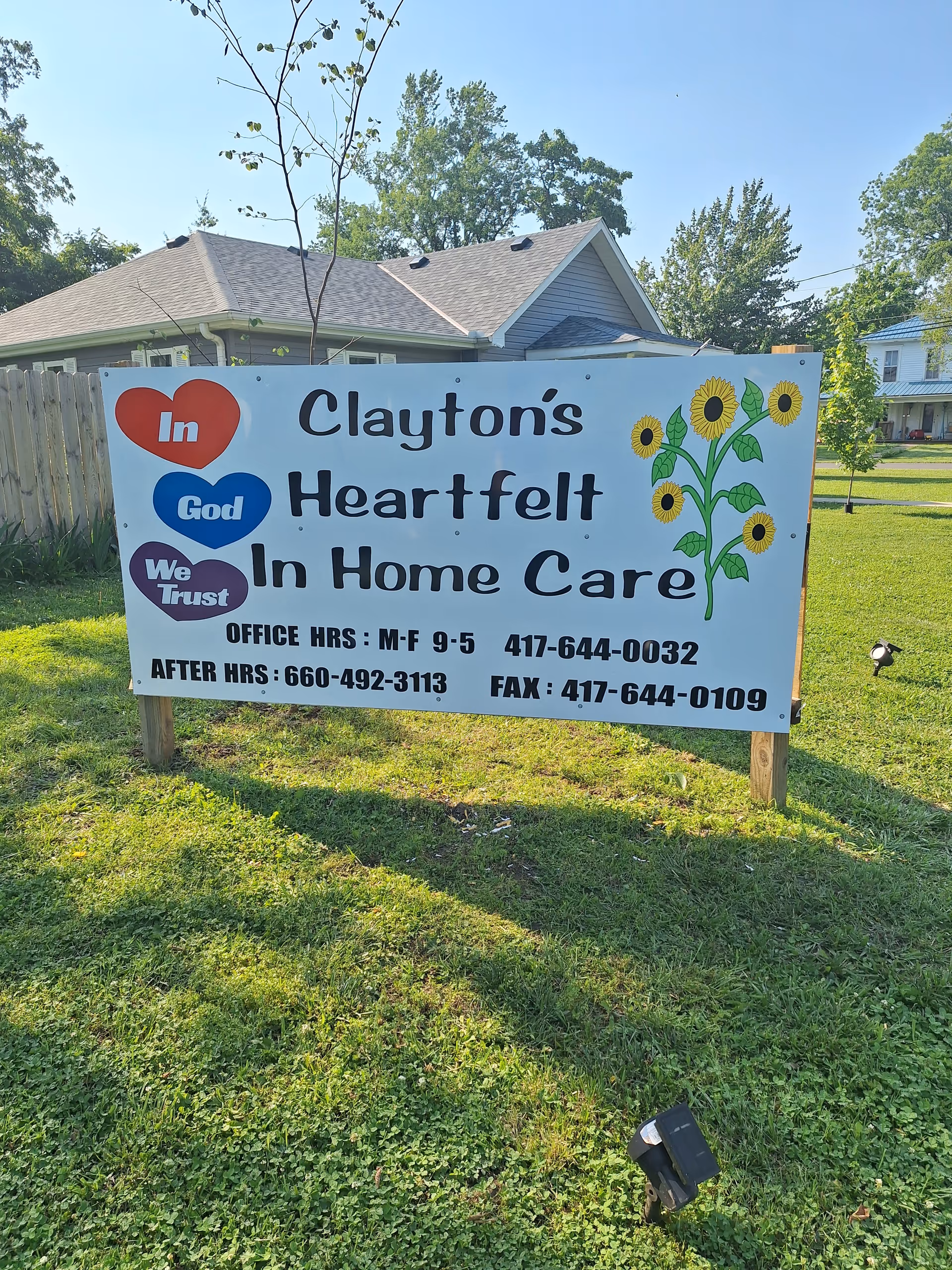 Outdoor sign reads Clayton's Heartfelt In Home Care beside a house and sunflowers.