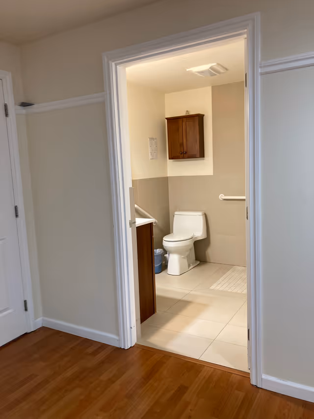 Doorway view of a small bathroom with toilet, sink, and wall cabinet.