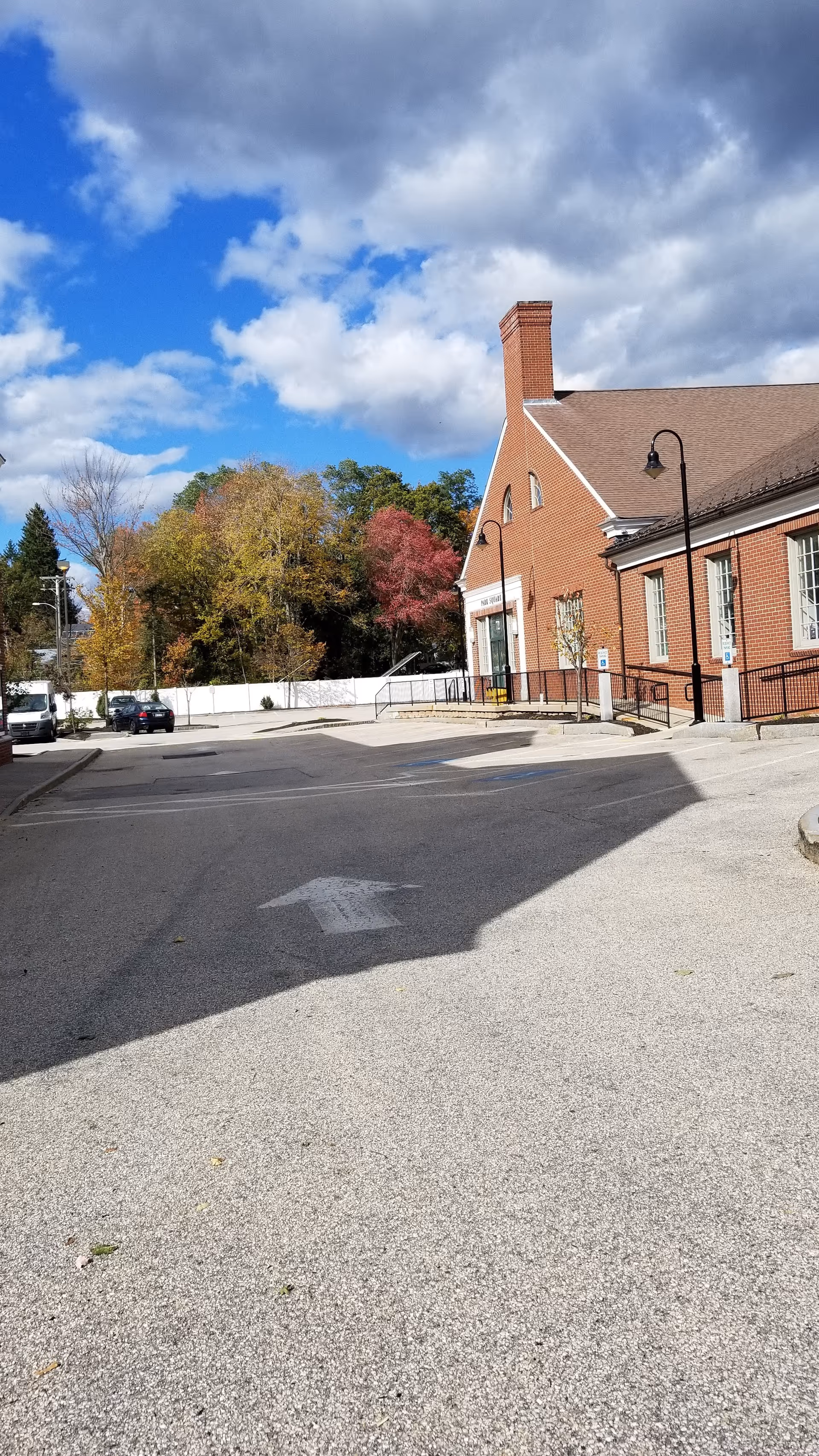 Front view of a brick facility with ramp entrance and autumn trees.