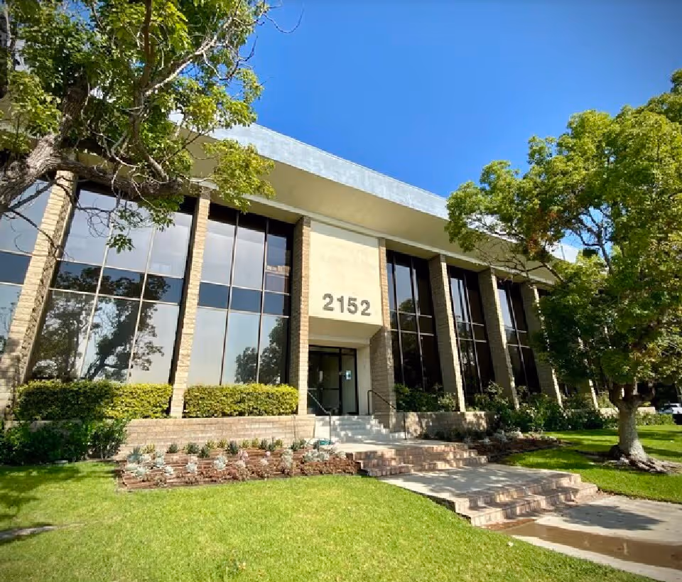 Front exterior of Interim HealthCare Irvine building with large glass windows and greenery.