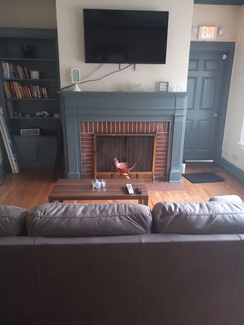 Living room with sofa, fireplace, mounted TV, and bookshelf.
