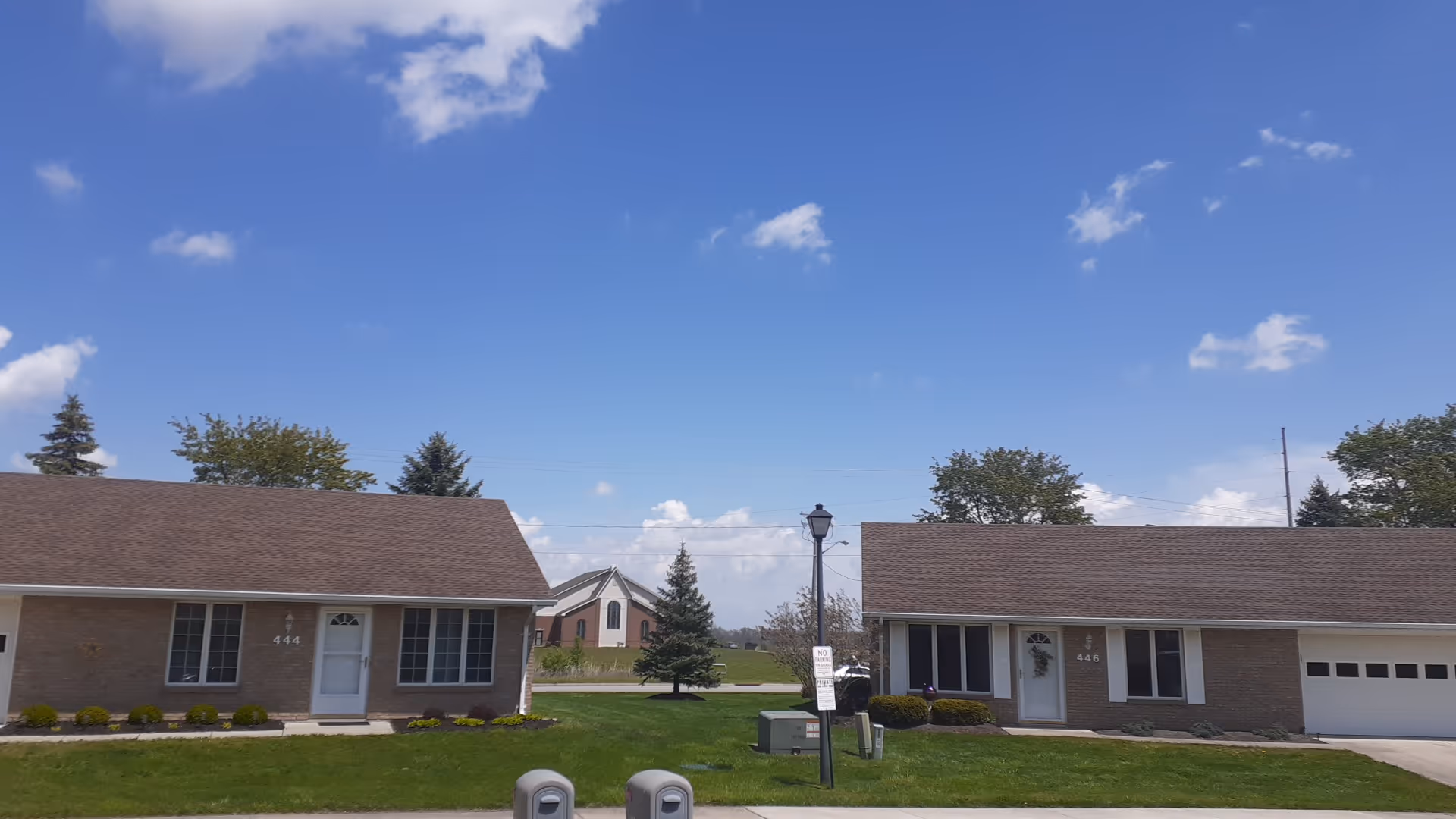 Two single-story brick buildings with manicured lawns under a blue sky.