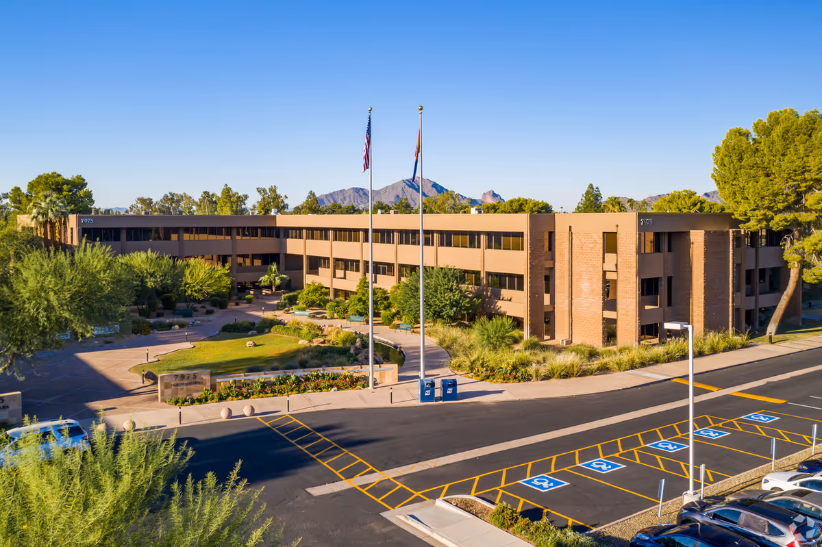 Exterior view of SPG Virtual Care facility: brick building with parking, flags, and landscaping.