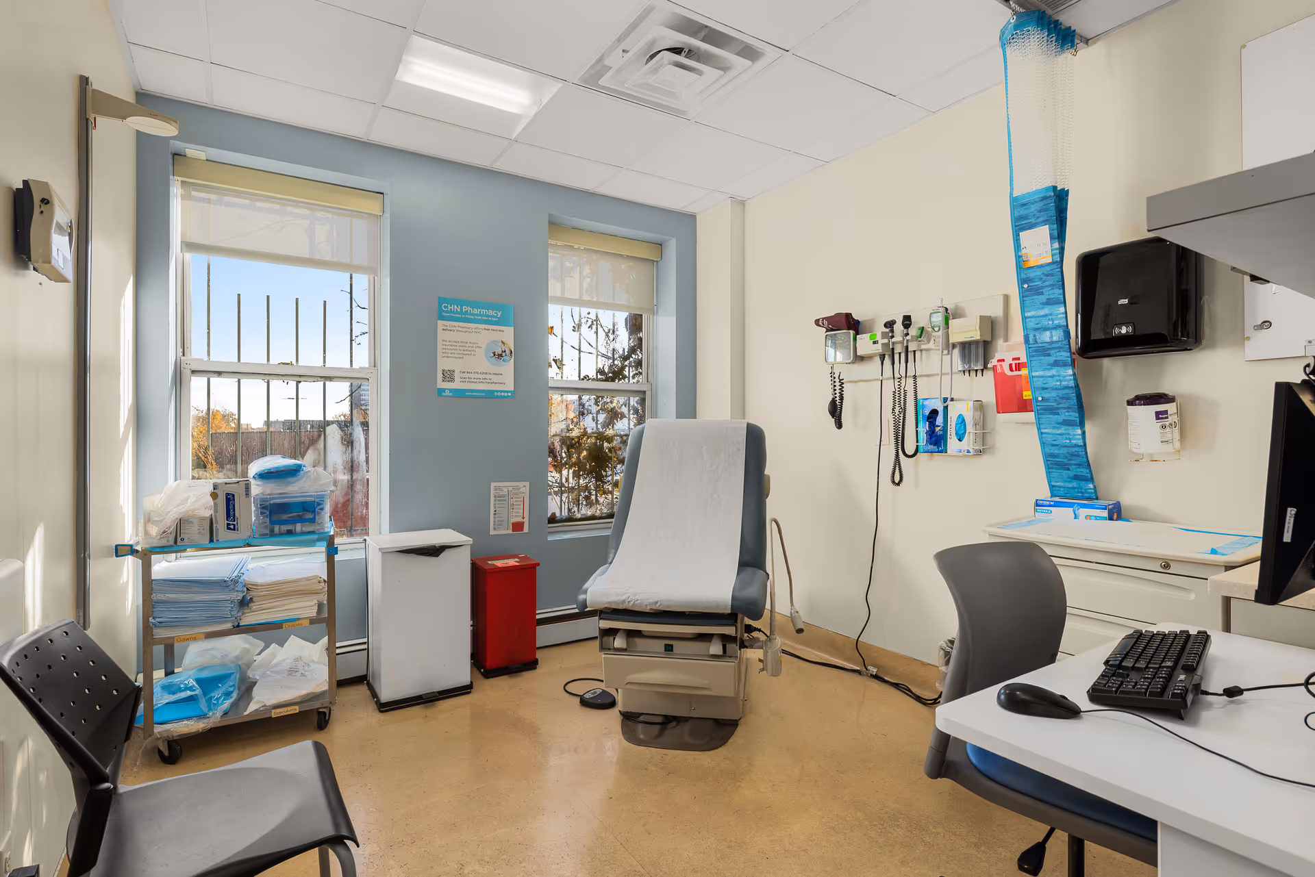 Clinical examination room features an exam chair, computer desk, and medical supplies.