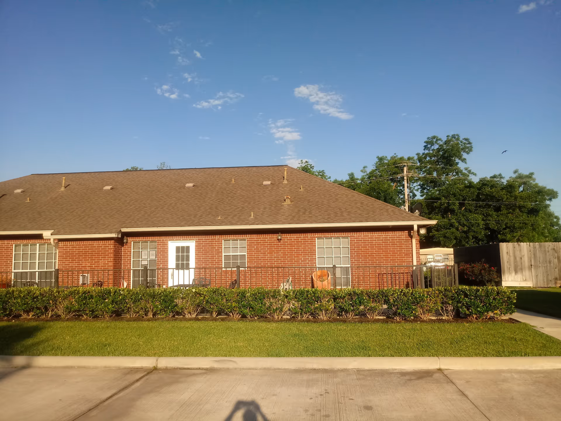 Single-story brick senior living facility exterior with manicured lawn and clear blue sky.