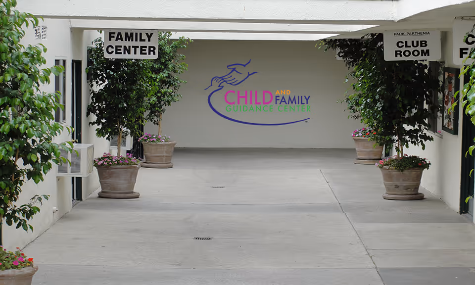 Sheltered corridor entrance to a Child and Family Guidance Center with plants and signs.