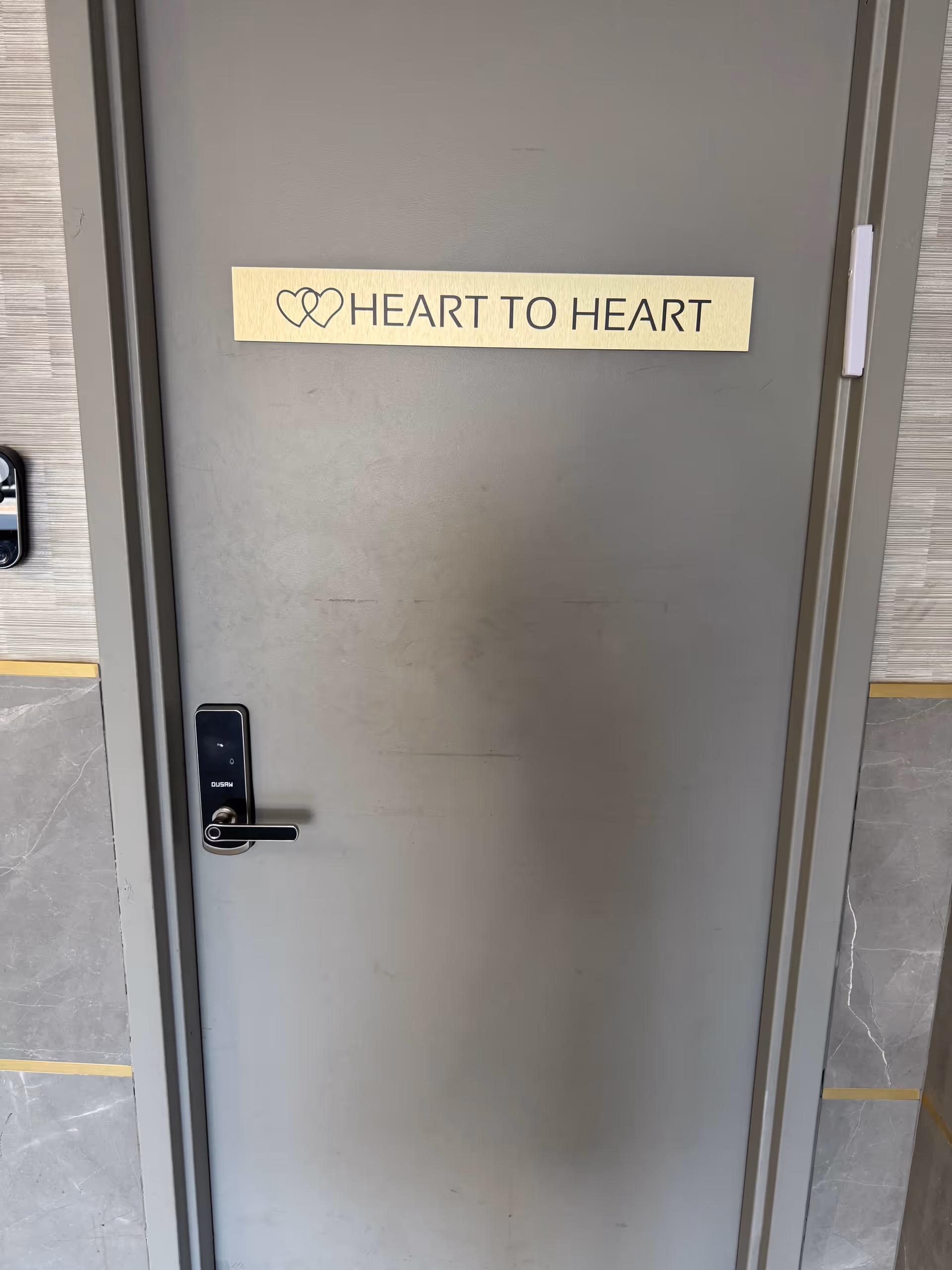 Grey metal door with beige Heart to Heart sign in a hallway