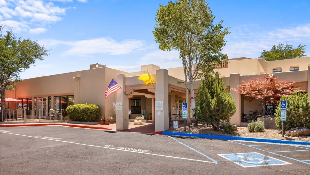 Exterior view of Brookdale Santa Fe entrance with flag, parking, and landscaped frontage.