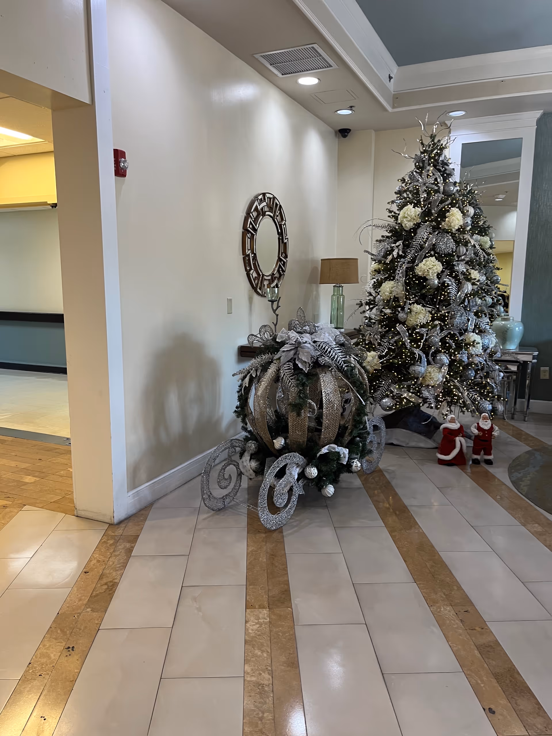 Holiday-decorated senior living facility lobby with a large Christmas tree and silver ornaments