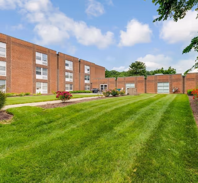 Brick Warren Place Senior Apartments building with a manicured lawn and walkway.