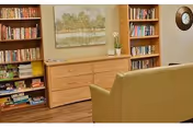 A cozy living room with tall bookshelves, a wooden cabinet, and a yellow sofa.