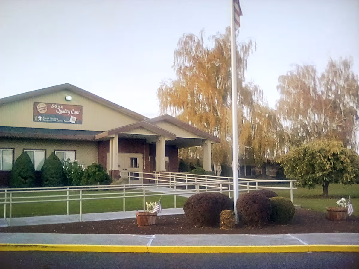 Front view of Avalon Health & Rehabilitation Center Pasco with ramp and flagpole.