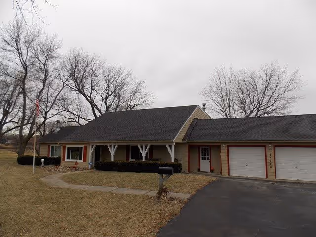 Single-story building with a front porch, flagpole, mailbox, and bare trees.