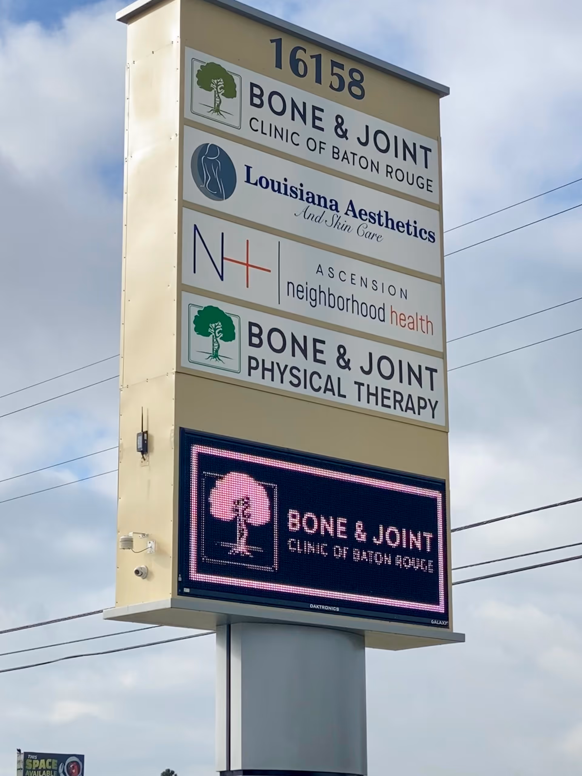 Tall outdoor signboard displaying multiple medical clinic logos, including Bone & Joint and Neighborhood Health.