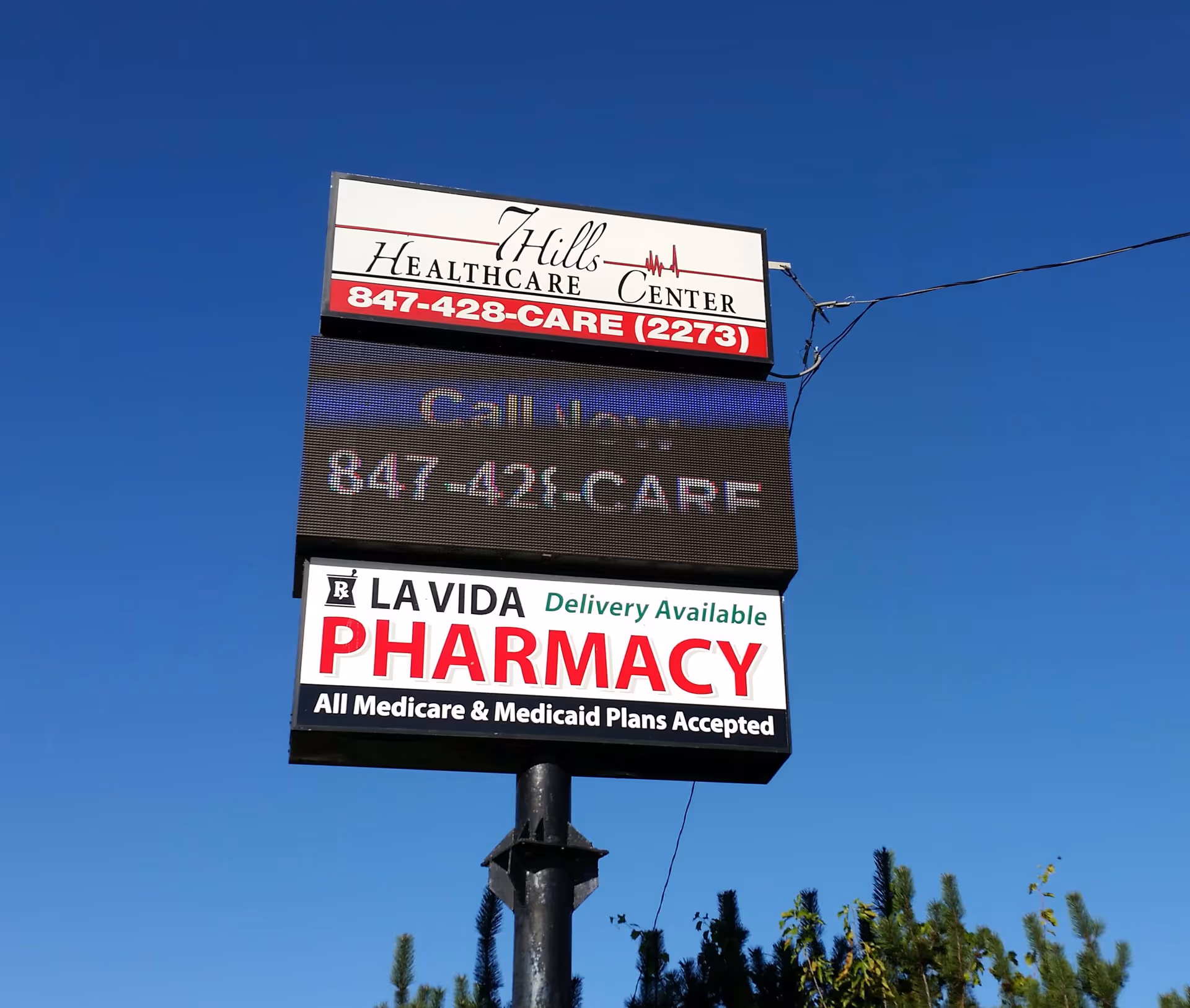 Outdoor sign for Hill Healthcare Center and pharmacy against clear blue sky.