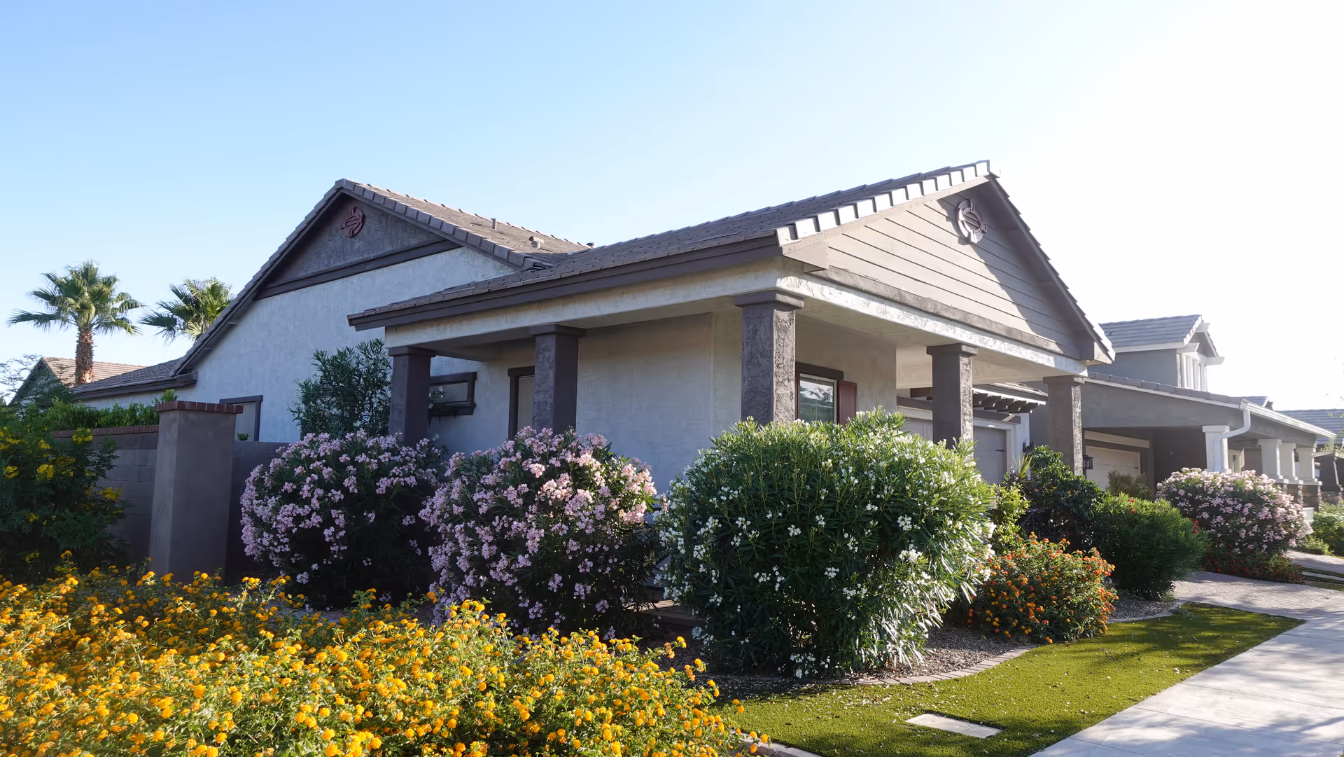 Senior living facility exterior with a covered entrance and landscaped flowering bushes.