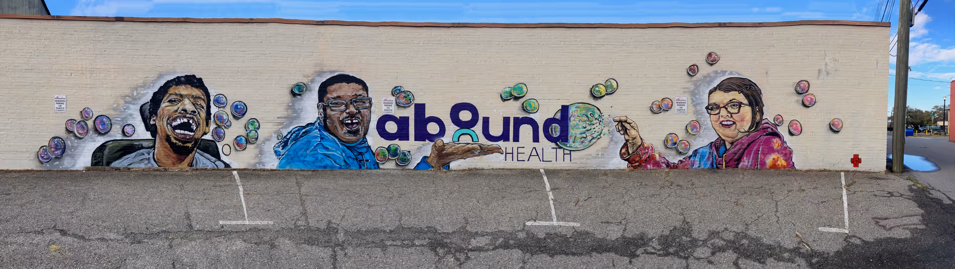 Exterior wall mural for Abound Health featuring laughing people and colorful bubbles.