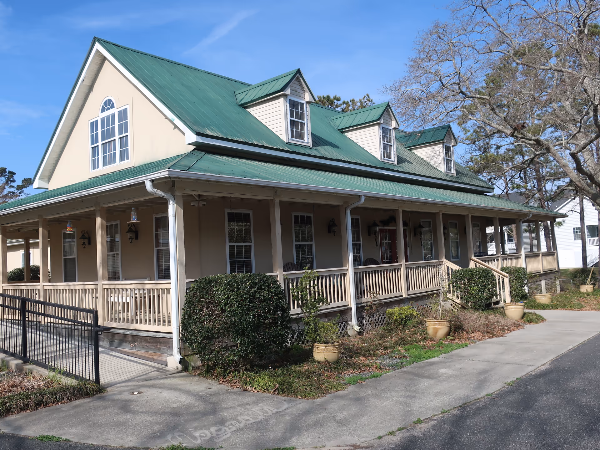 Exterior view of Magnolias of Myrtle Beach with a green roof and long porch.