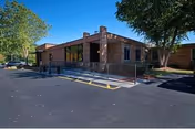 Brick single-story senior living facility entrance with ramp and parking lot.