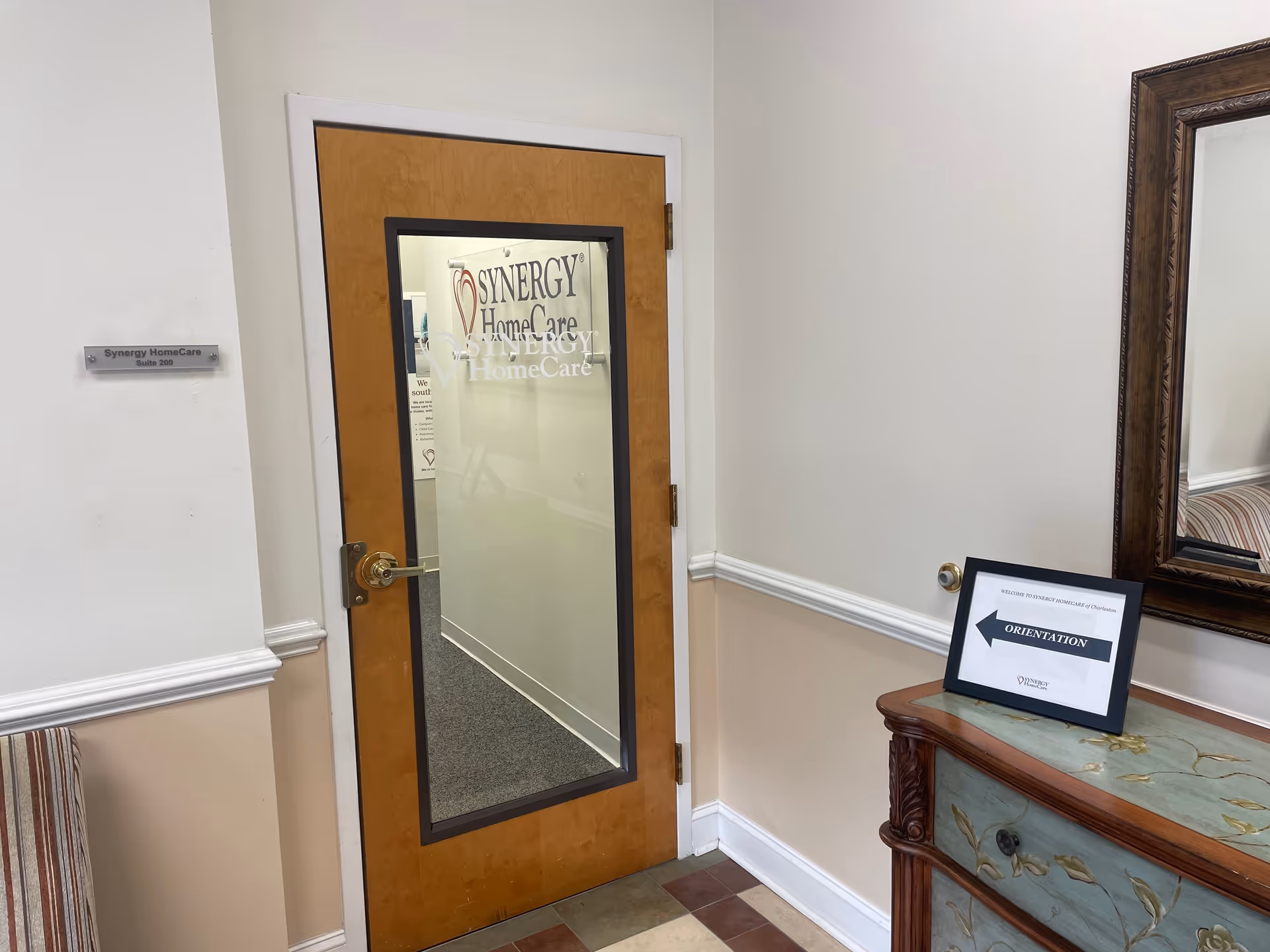 Interior hallway of a senior care facility with a wooden door and mirror.