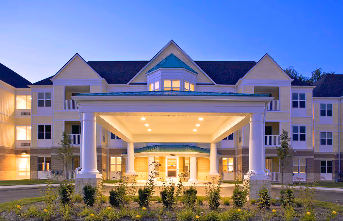 Exterior view of a senior living facility entrance under a covered porte-cochère.