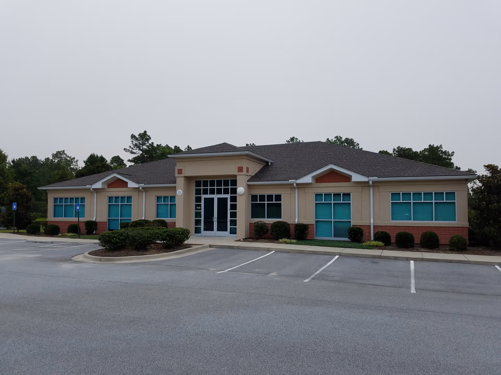 Front view of Enhabit Home Health building with parking and trimmed shrubs.