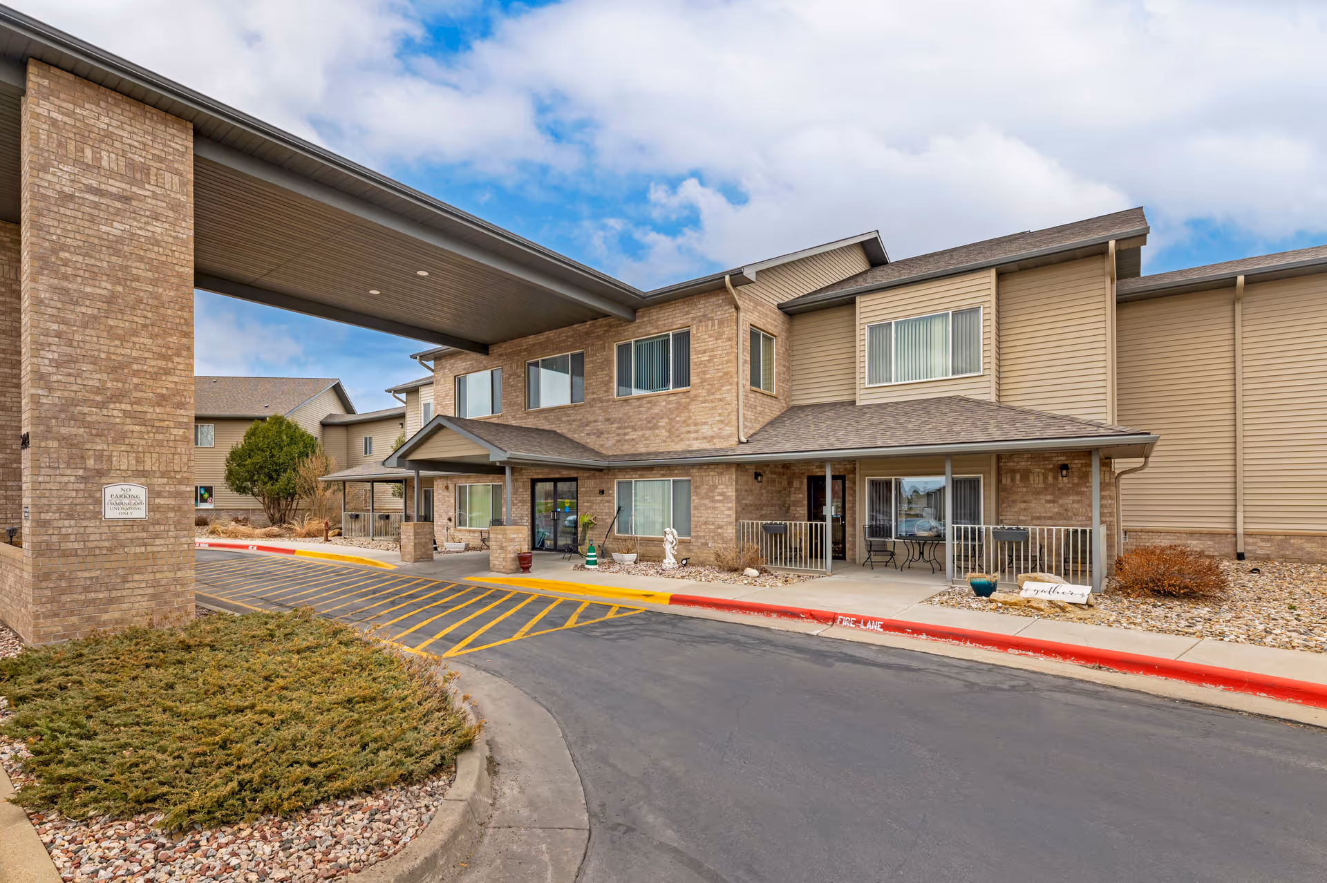 Exterior view of Arrowhead Lodge Senior Living with brick building, covered entry, and landscaping.