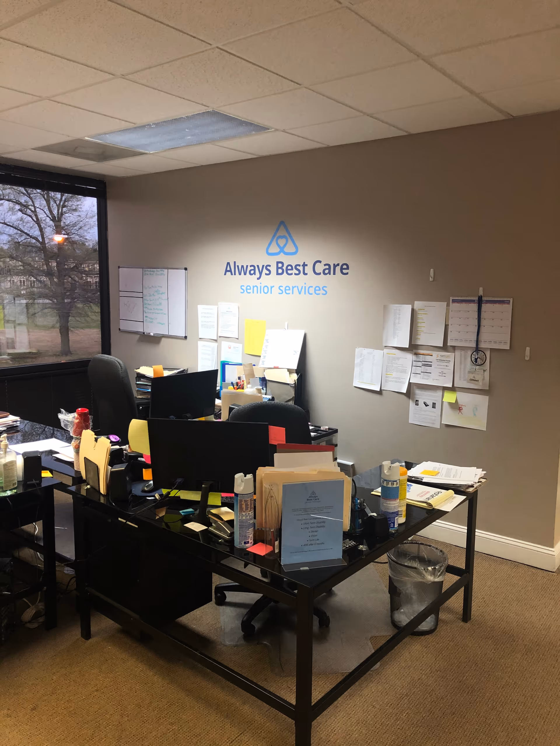 Interior office area with desks, supplies, and a wall sign reading Always Best Care senior services.
