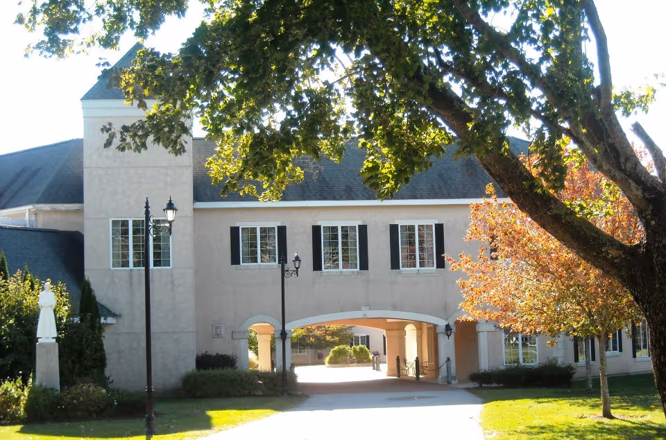 Front view of Villa at St Antoine with archway entrance and trees.