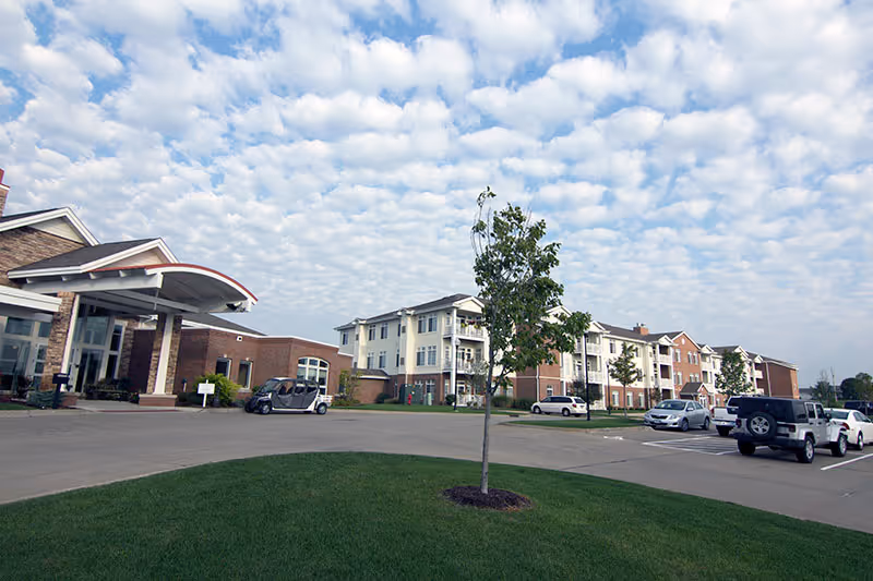 Exterior view of Charryett House senior living campus with parked cars and green lawn.