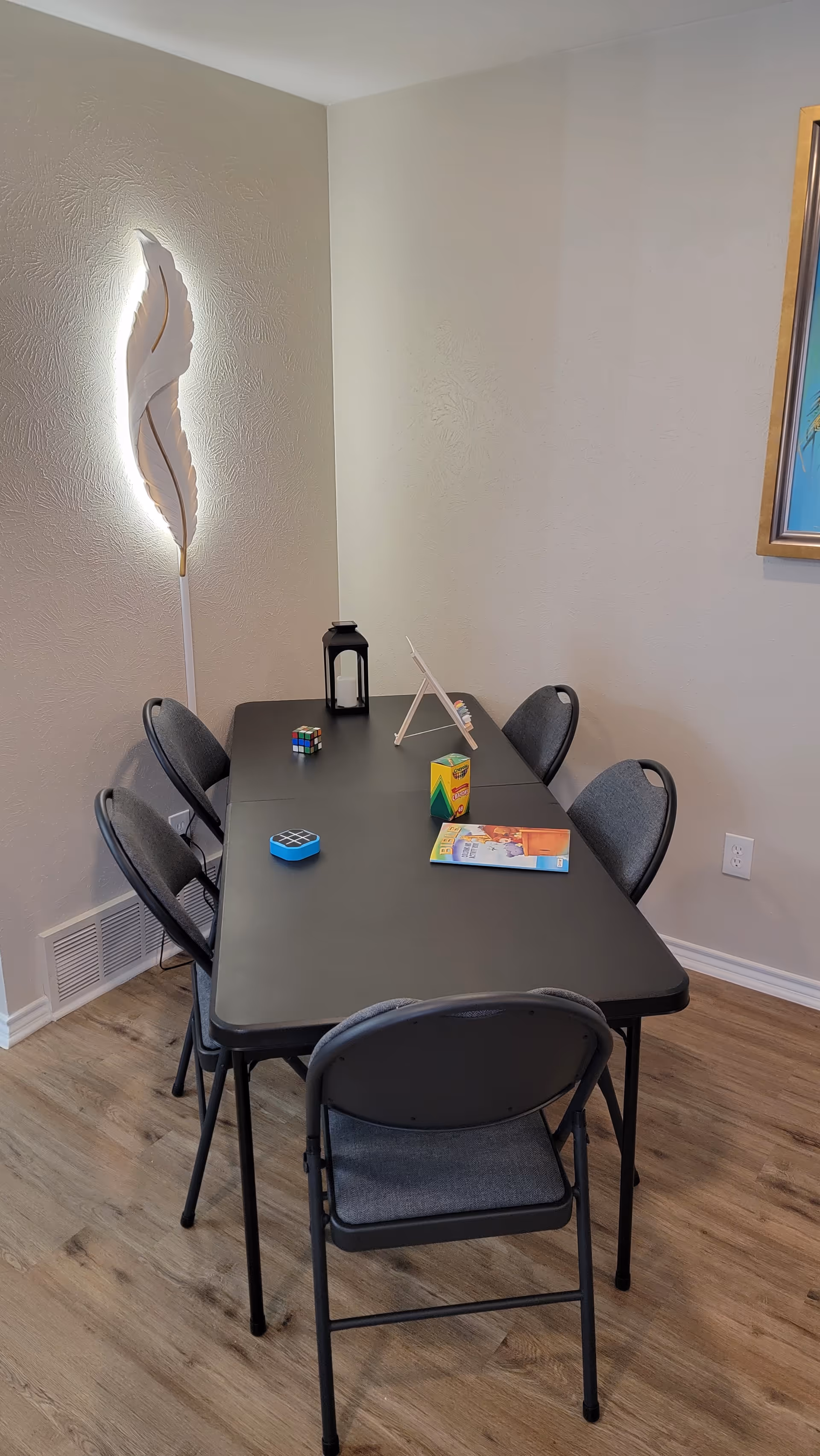 Indoor room with a rectangular table, six folding chairs, and tabletop game items.