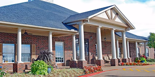 Exterior view of The Gardens at Quail Springs, brick senior living facility with covered porch.
