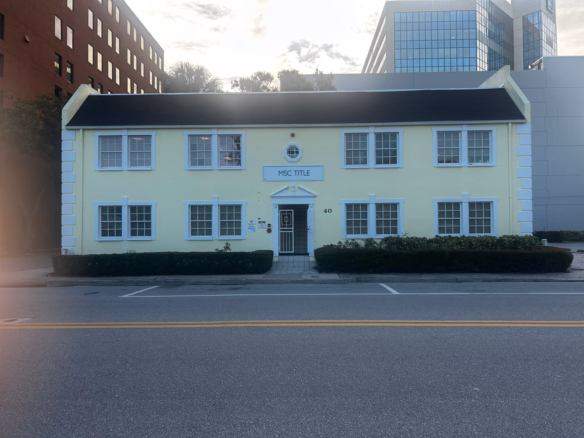 Small pale yellow two-story building with white trim and a central front door.