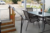 Outdoor patio area with a metal table and chairs beside steps and railing.