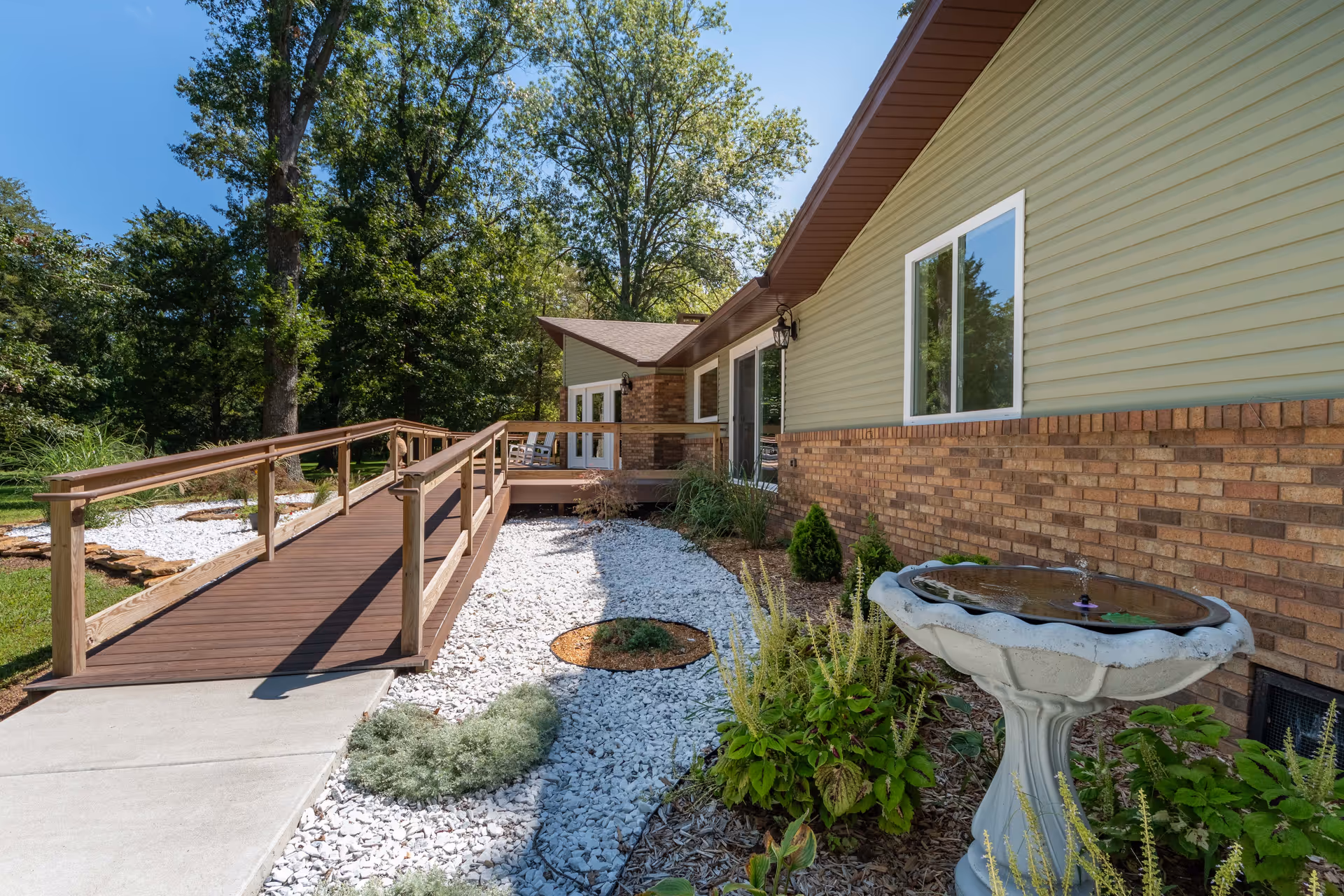 Exterior view of a single-story senior living building with a wooden ramp and landscaped yard.