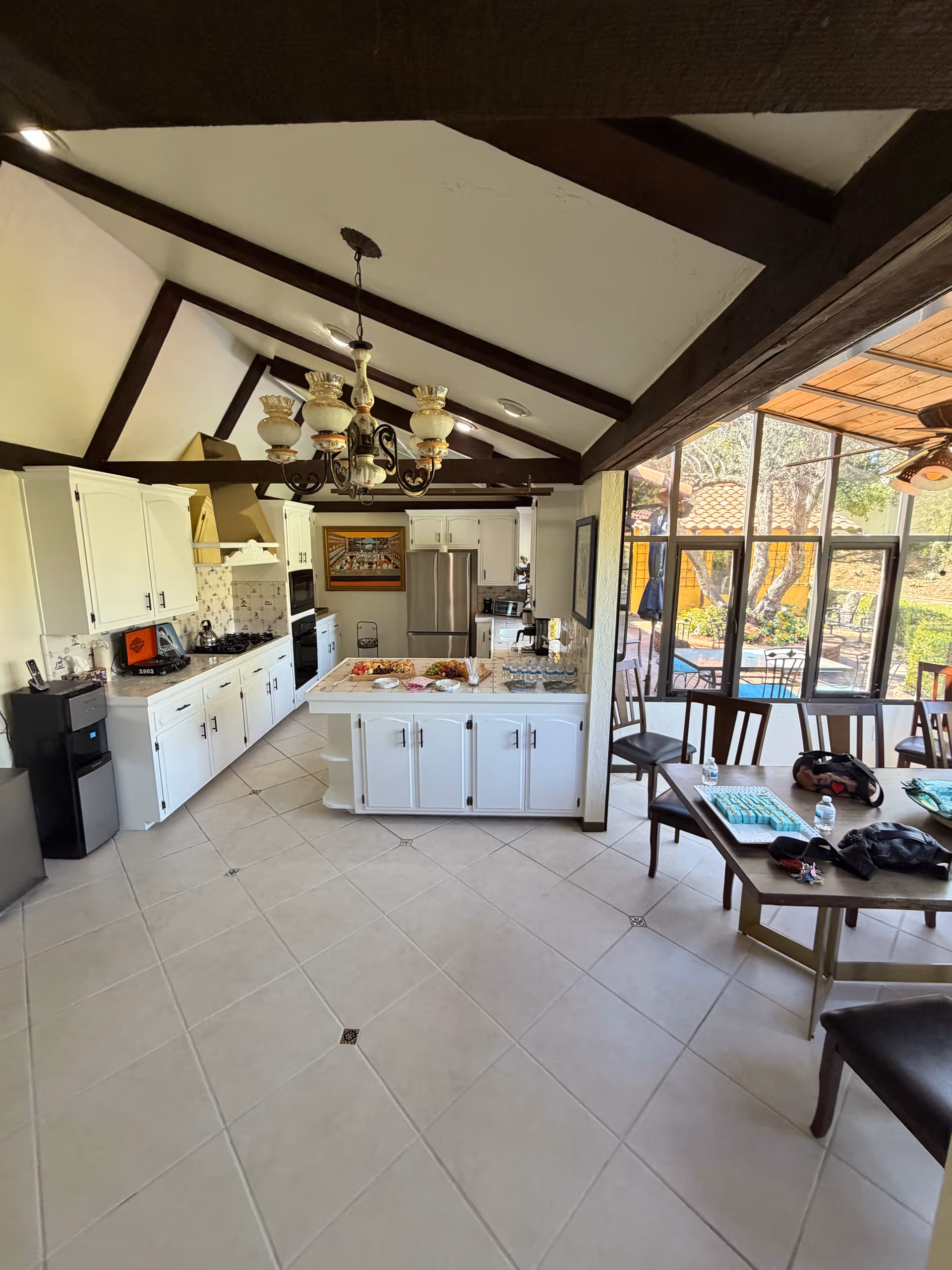 Bright open kitchen with white cabinets, island, chandelier, and adjacent dining area.