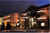 Nighttime exterior of Canterbury Manor, a multi-story senior living building with balconies and entrance.