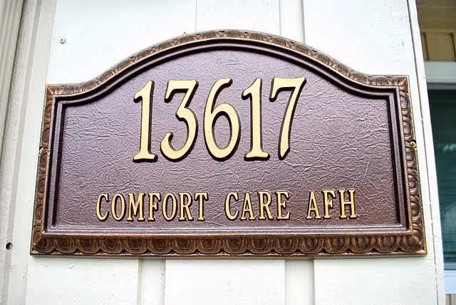 Brown plaque with 13617 and 'Comfort Care AFH' on a house exterior.
