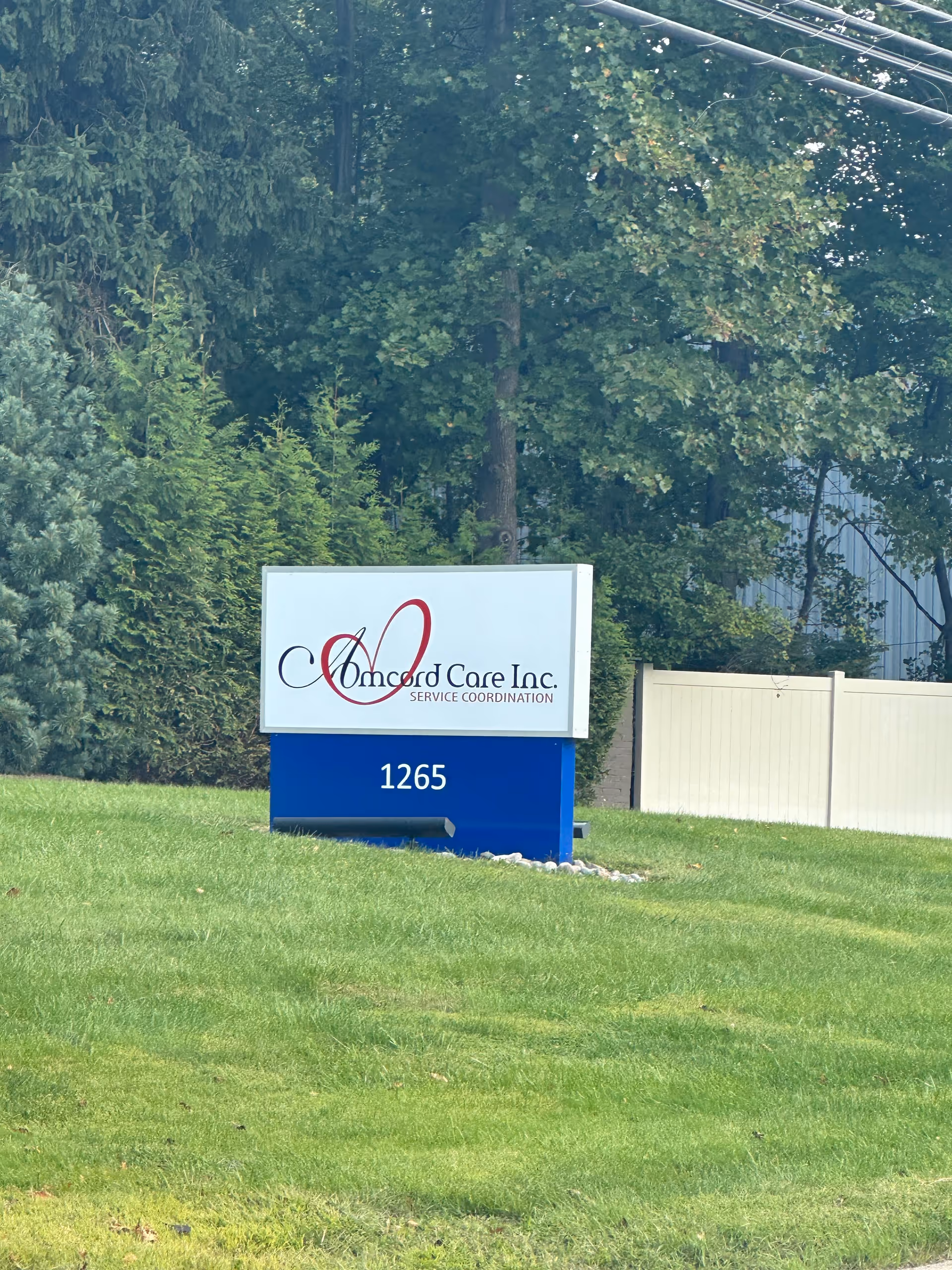 Outdoor scene with Amcord Care Inc. service coordination sign on a grassy lawn.