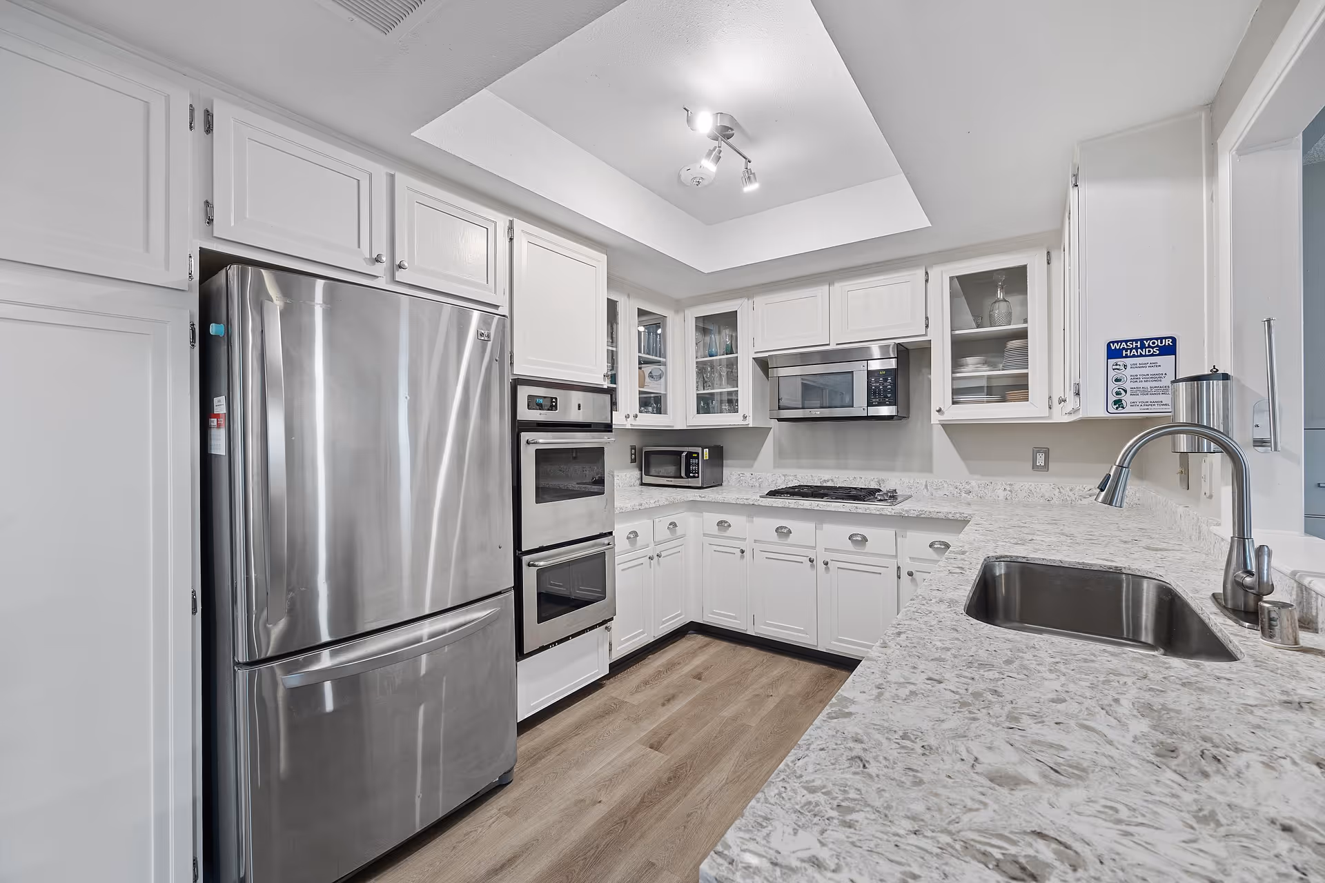 Bright, modern white kitchen with stainless steel appliances and marble countertops.
